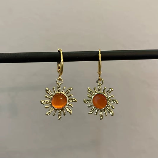 Boucles d'Oreilles Soleil Or suspendues sur une barre noire