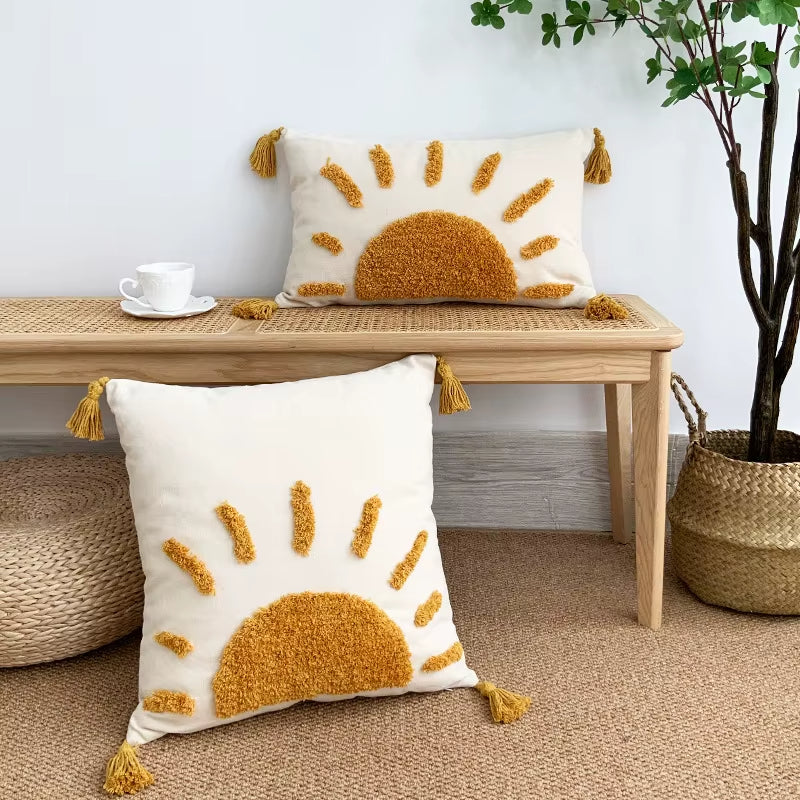 Housse de Coussin Tufté Soleil posée sur le sol et une table avec une plante verte à droite